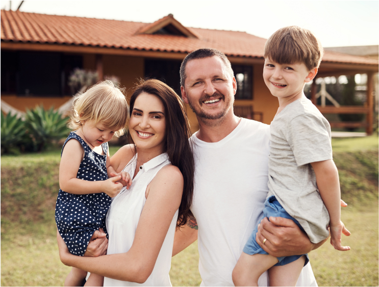 A happy family of four standing in front of their home, symbolizing trust and satisfaction with Zown services.