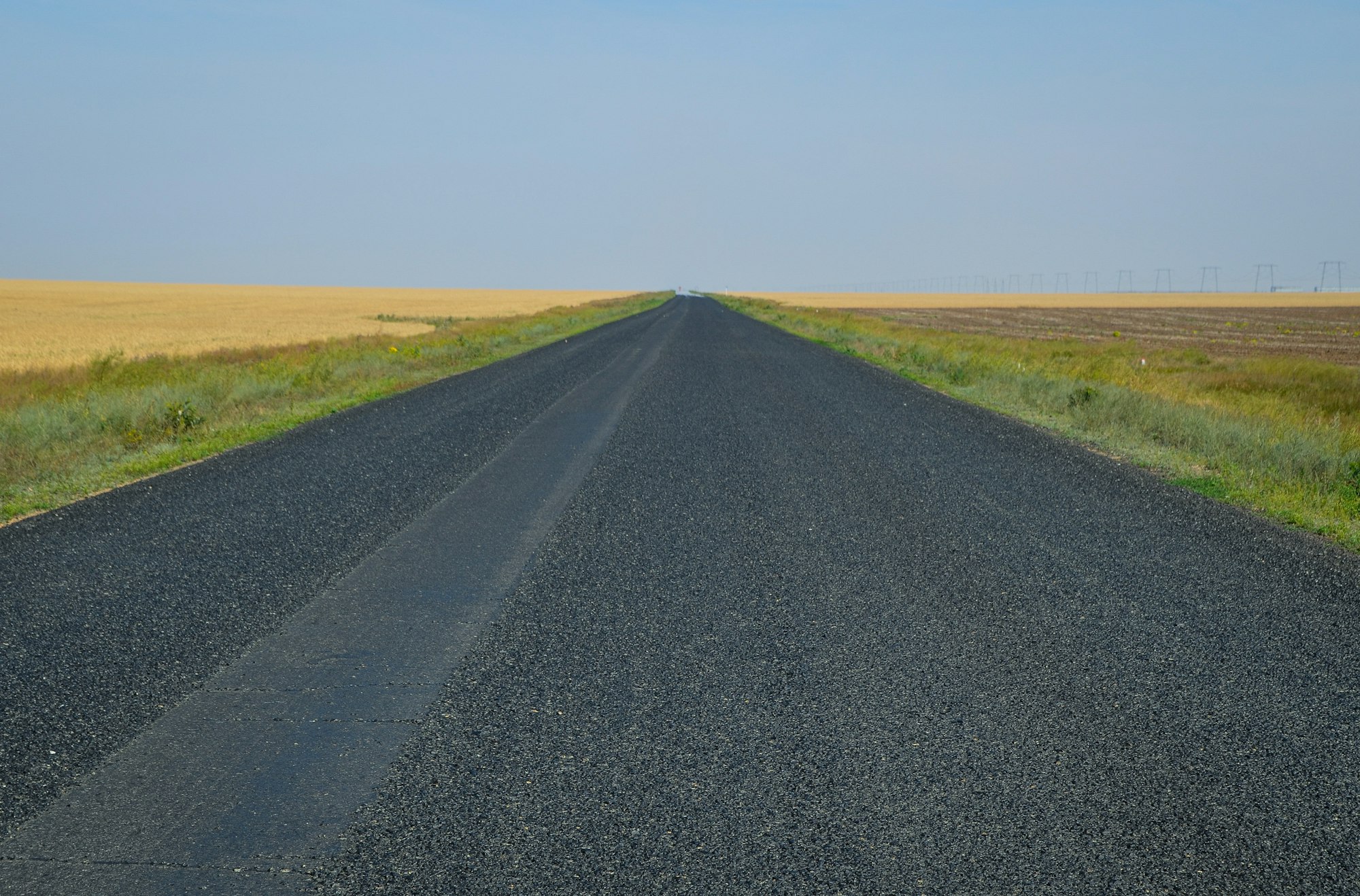 Long straight road stretching toward the horizon through open countryside