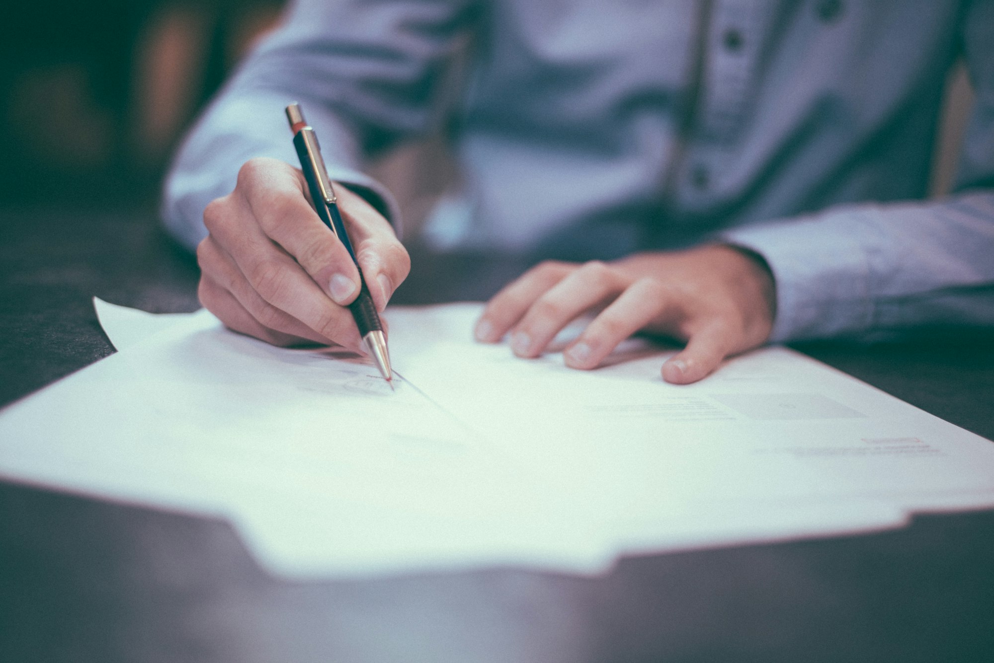 Close-up of a hand signing a document with a pen