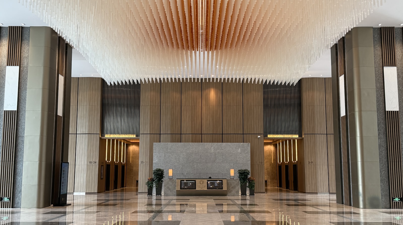 A large modern condominium lobby with marble floors, wood panelling and a decorative ceiling