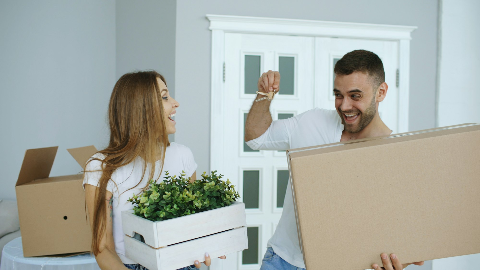 Happy couple holding house keys and moving boxes in their new home