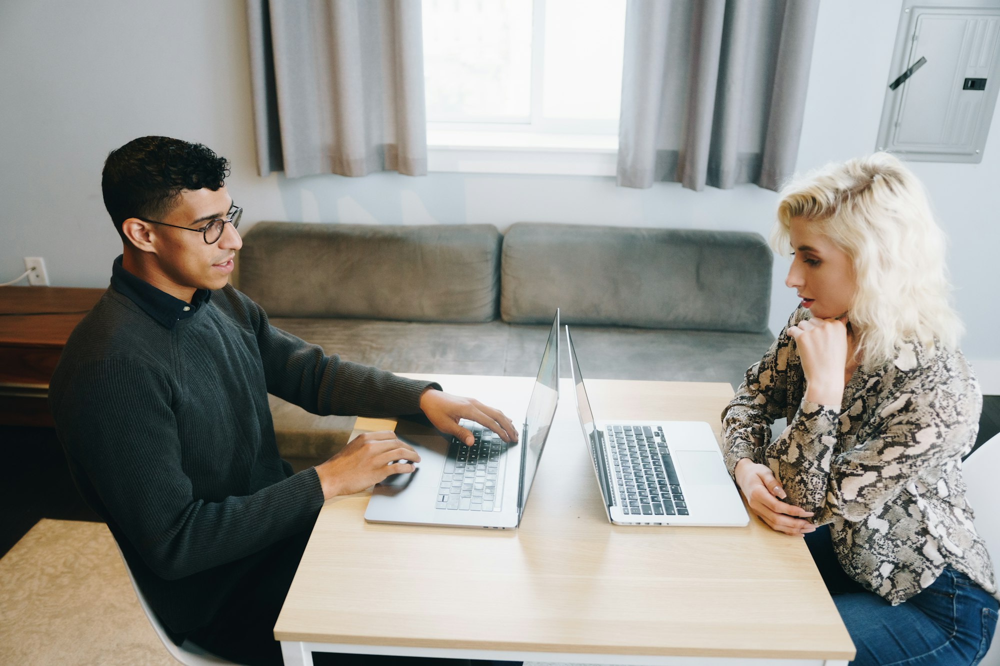 Couple sitting at a table with laptops reviewing their home-buying budget