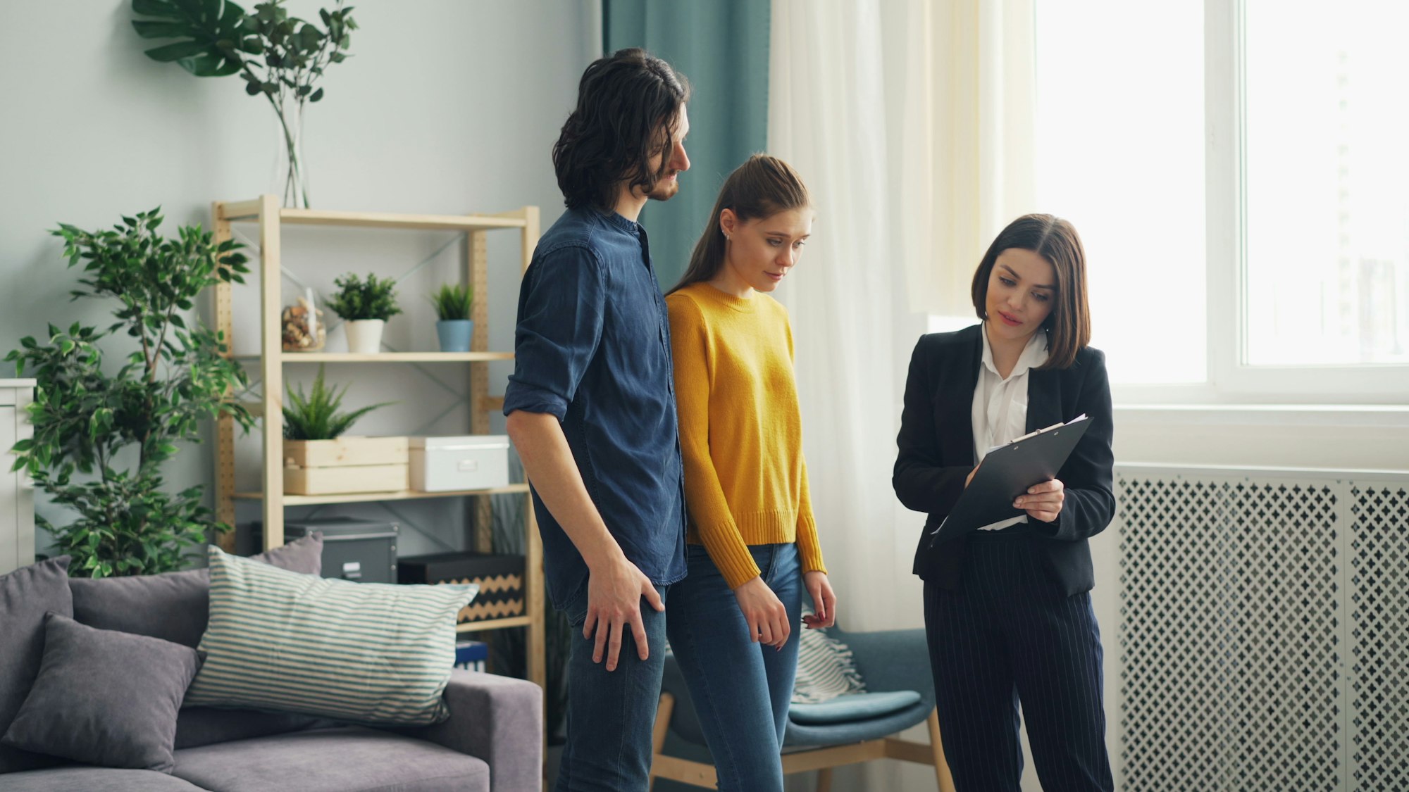 Couple reviewing a clipboard checklist with a real estate agent during a home tour